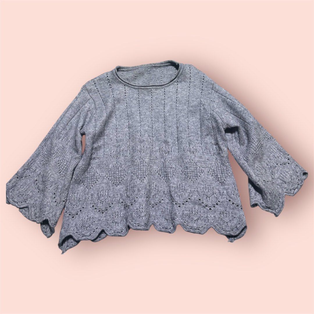 Grey Knit Sweater with Bell Sleeves (Category: Longsleeves) located in Rosario. Submitted by preloveditems2002 (Listing ID 1461044817, Image 1). Description: - Light grey knit sweater - Features a pretty lace-like pattern on hem and sleeves - Bell-shaped, flared sleeves - Versatile for layering or wearing on its own - Comfortable and stylish design.