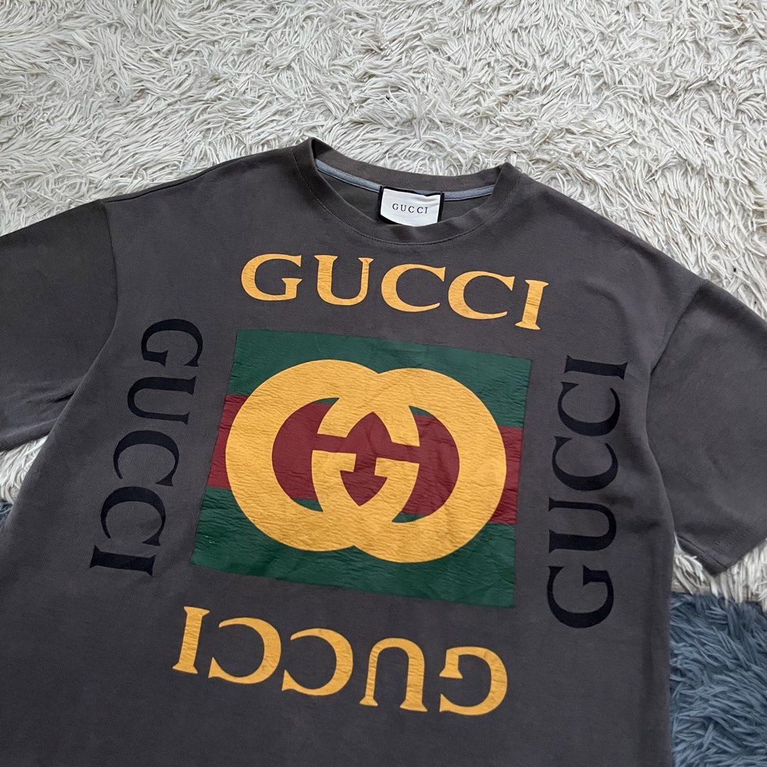 Gucci T-shirt (Category: Tshirts & Polo Shirts ) located in Iloilo. Submitted by illcitythriftedco. (Listing ID 1461072934, Image 2). Description: - Grey Gucci T-shirt - Features iconic GG logo print - Logo displayed on front and sides - Versatile statement piece - Pairs well with jeans or shorts.