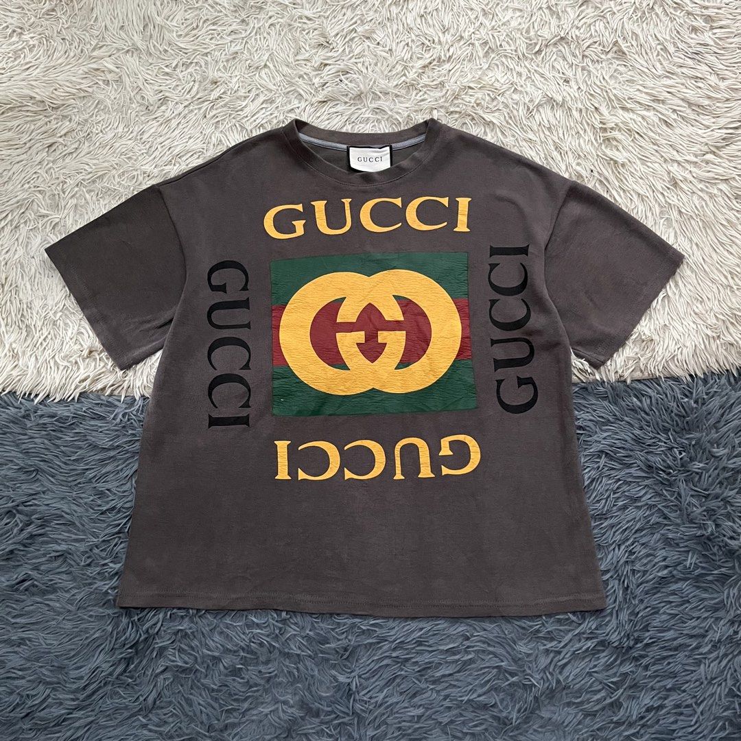 Gucci T-shirt (Category: Tshirts & Polo Shirts ) located in Iloilo. Submitted by illcitythriftedco. (Listing ID 1461072934, Image 1). Description: - Grey Gucci T-shirt - Features iconic GG logo print - Logo displayed on front and sides - Versatile statement piece - Pairs well with jeans or shorts.