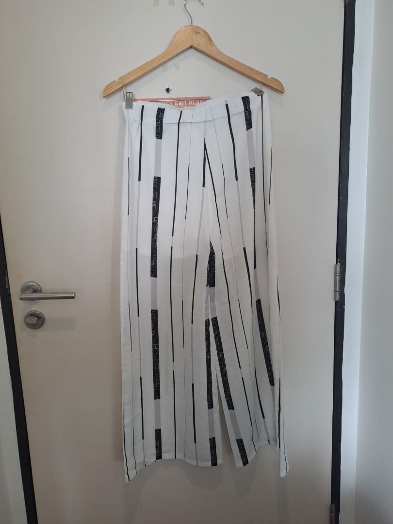High waisted trousers (Category: Other Bottoms) located in Mandaluyong City. Submitted by epicowl-c93c (Listing ID 1460945369, Image 2). Description: pair of white high-waisted wide-leg trousers featuring a distinct black abstract geometric vertical stripe print. The pattern combines continuous vertical lines with alternating broken block segments. The garment is constructed from a lightweight woven fabric and includes a flat front waistband..