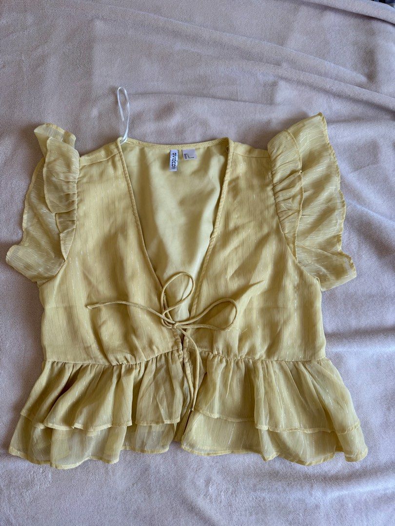 H&M Yellow Ruffle Tie Front Sheer Blouse (Category: Blouses) located in Bacolod City. Submitted by bellabianca_closet (Listing ID 1461050067, Image 2). Description: Disclaimer: 1st photo not mine - Cute yellow top from H&M - Sheer material with subtle vertical stripes - Features ruffle sleeves - Tiered peplum hem for a flattering silhouette - Adjustable tie front detail at the bust - Versatile for dressing up or down - Ideal for summer wear.