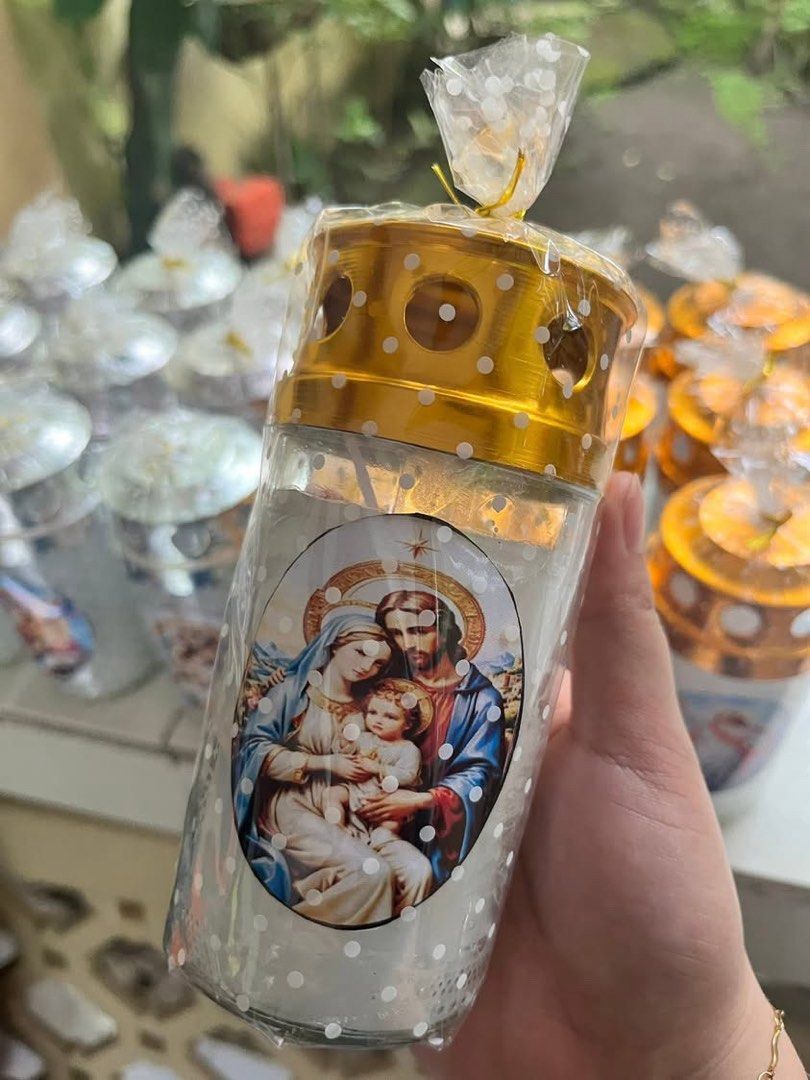 Chunks Medium Lamp (Category: Home Fragrance) located in Cavite. Submitted by prelovedclothesbyc_ (Listing ID 1460927737, Image 1). Description: -Medium Size -3 pcs available - Features an image of the Holy Family. - Comes with a decorative gold lid featuring cutouts. - White glass candle with a subtle white polka dot pattern. - Wrapped in clear cellophane with a gold tie. - Ideal for home decor or as a thoughtful gift..