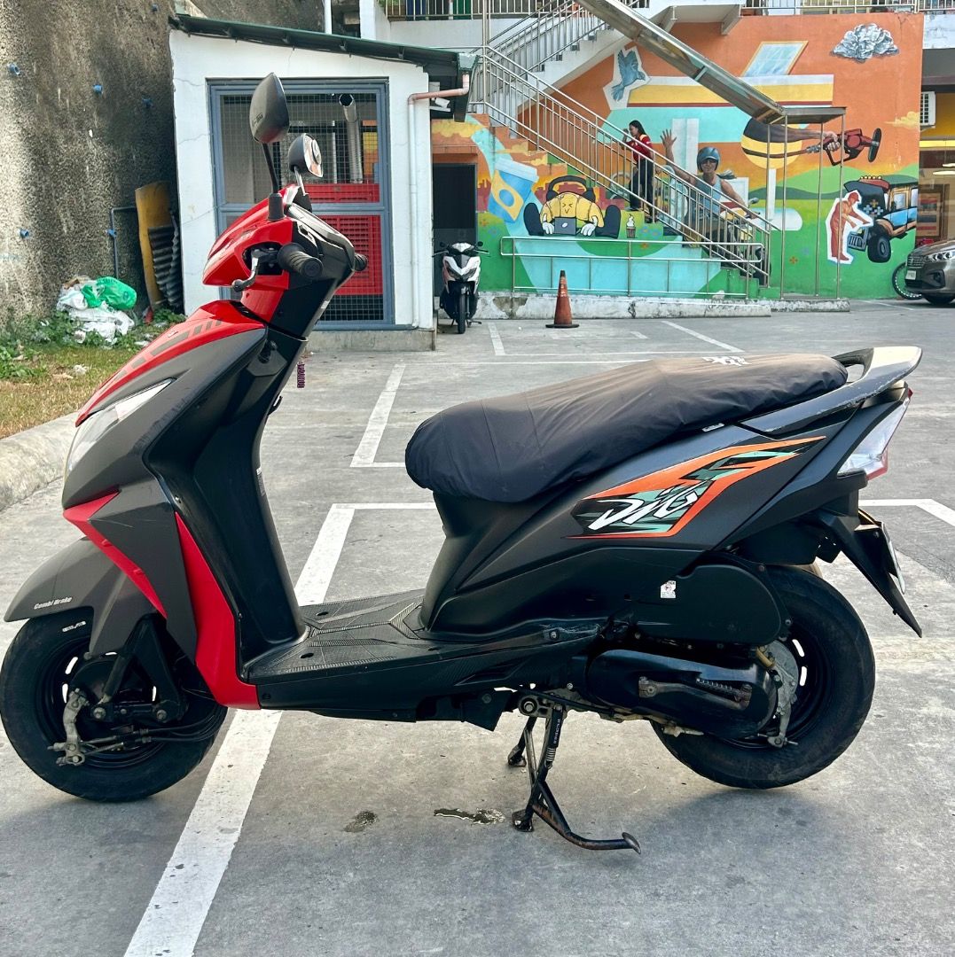 Honda Dio Red Scooter (Category: Motorbikes for Sale) located in Caloocan City. Submitted by mysticwomen (Listing ID 1461001211, Image 2). Description: Red Honda Dio scooter. Dashboard shows mileage at 054282. Seat has a black cover with 'Dio' logo. Ready for a new rider. Great for getting around..