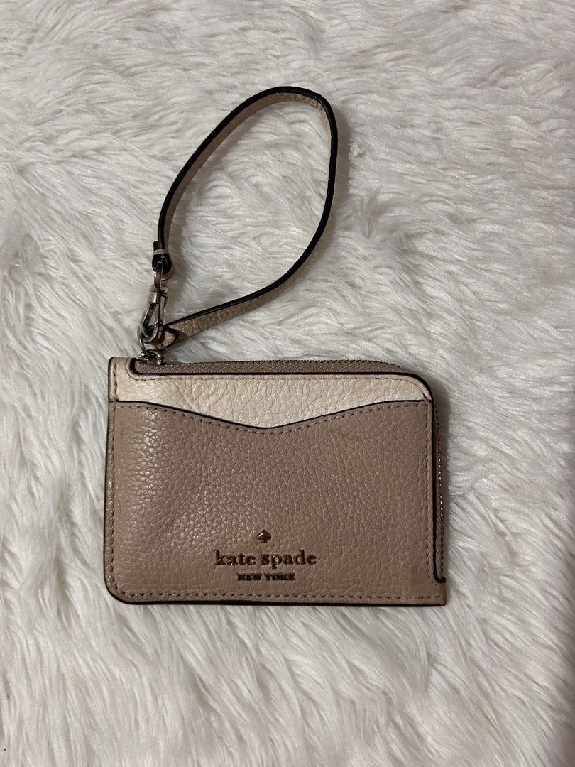 Kate Spade Leila Small Cardholder Wristlet (Category: Wallets & Card holders) located in Cavite. Submitted by cleanupsale20 (Listing ID 1461056056, Image 1). Description: - Stylish Kate Spade card holder - Elegant beige and cream color block design - Convenient zippered compartment for essentials - Clear ID window on the back for easy access - Includes a detachable wrist strap for versatility - Compact dimensions: 11cm x 8cm - Ideal for organizin