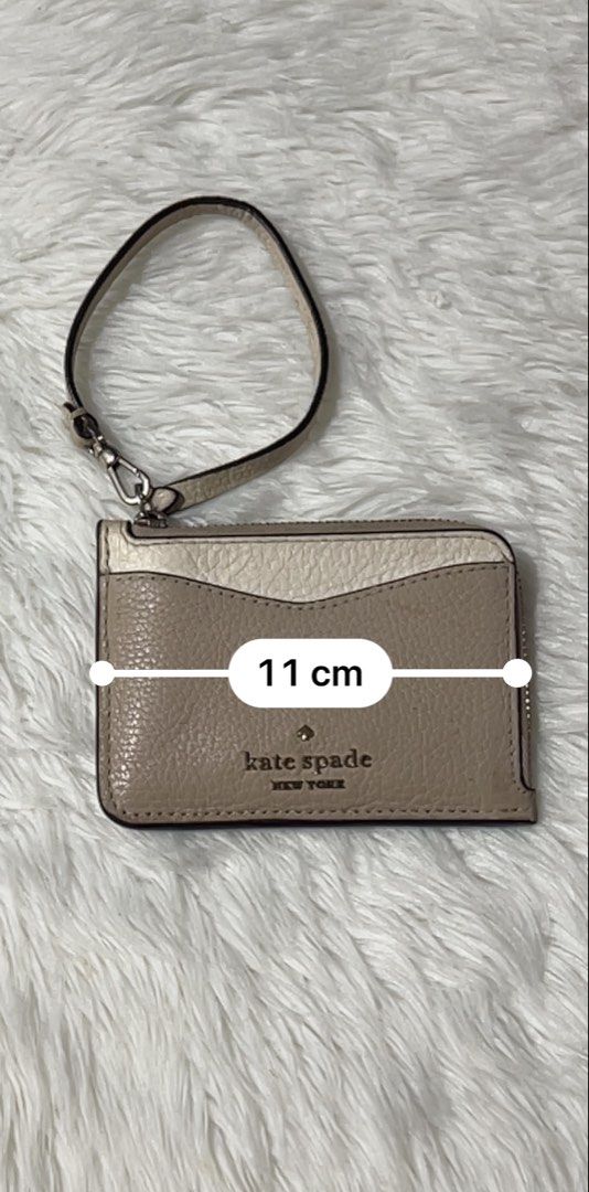Kate Spade Leila Small Cardholder Wristlet (Category: Wallets & Card holders) located in Cavite. Submitted by cleanupsale20 (Listing ID 1461056056, Image 3). Description: - Stylish Kate Spade card holder - Elegant beige and cream color block design - Convenient zippered compartment for essentials - Clear ID window on the back for easy access - Includes a detachable wrist strap for versatility - Compact dimensions: 11cm x 8cm - Ideal for organizin