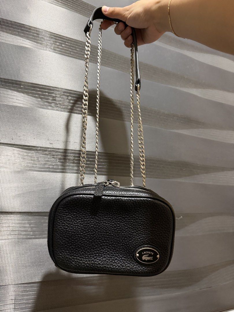Lacoste Leather Crossbody Bag with Chain Strap (Category: Cross-body Bags) located in Muntinlupa City. Submitted by biancaagbscloset (Listing ID 1461107092, Image 1). Description: Like new condition - Authentic Lacoste black leather crossbody bag - Features a pebbled texture - Silver chain strap (adjustable for shoulder or crossbody wear) - Interior zipped pocket for secure storage - Small and compact, perfect for essentials - Clean inside and ou