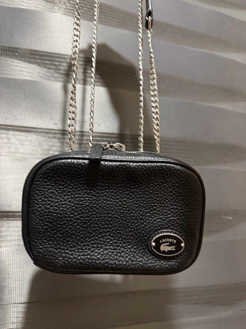 Lacoste Leather Crossbody Bag with Chain Strap (Category: Cross-body Bags) located in Muntinlupa City. Submitted by biancaagbscloset (Listing ID 1461107092, Image 3). Description: Like new condition - Authentic Lacoste black leather crossbody bag - Features a pebbled texture - Silver chain strap (adjustable for shoulder or crossbody wear) - Interior zipped pocket for secure storage - Small and compact, perfect for essentials - Clean inside and ou