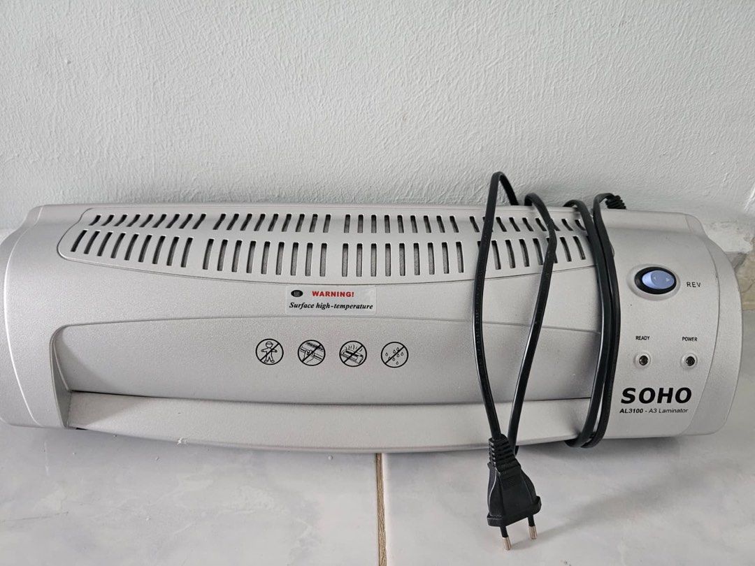 Laminating machine (Category: Other Stationery & Craft) located in Singapore. Submitted by _she.artshrk (Listing ID 1461065172, Image 1). Description: - SOHO AL3100 A3 Laminating Machine - Color: Silver - Condition: Good, pre-owned - Features: 'REV' button for jam reversal, 'READY' and 'POWER' indicator lights - Suitable for A3 and smaller size documents - Ideal for protecting photos, certificates, and important papers.
