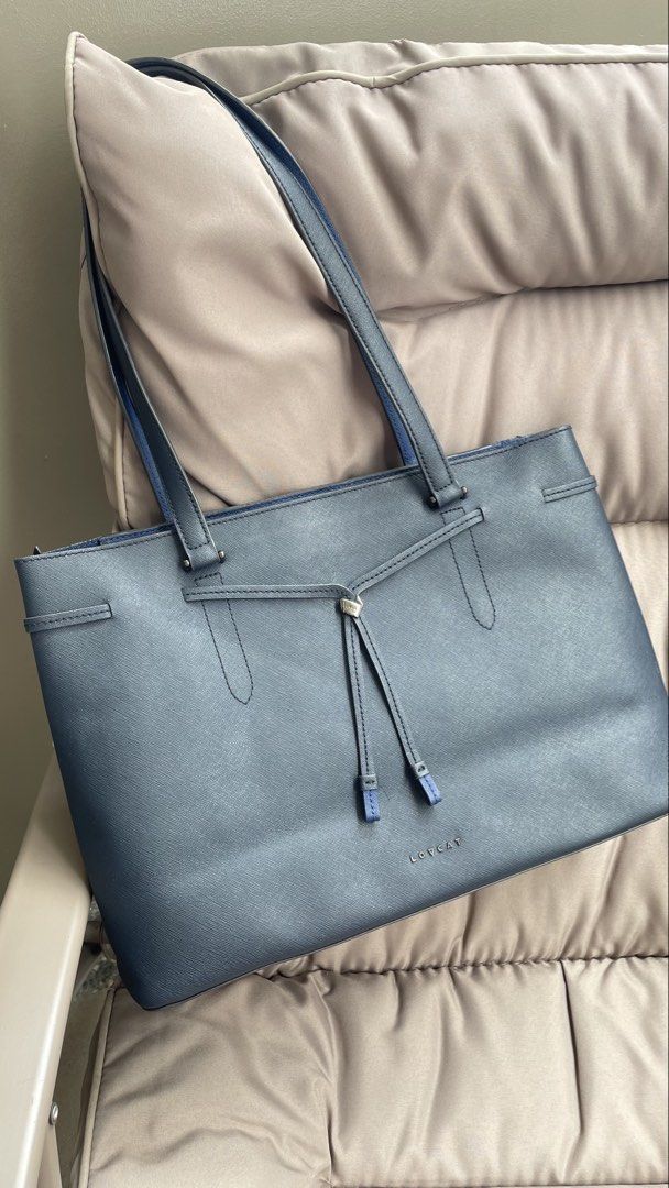 LOVE CAT Navy Blue Tote Bag (Category: Tote Bags) located in Pasig City. Submitted by roseyyylife (Listing ID 1461100530, Image 1). Description: Navy blue tote bag from LOVE CAT. Has a zip closure for the main compartment. Inside, there are zip pockets. The interior is a bright blue. The bag has a textured finish. Handles are navy blue with a blue lining. Measures about 14 inches wide..