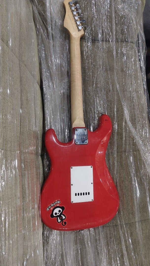 Mavis Red Electric Guitar with Stickers (Category: Musical Instruments) located in Manila. Submitted by joshespino71762 (Listing ID 1460927879, Image 2). Description: - Red Mavis electric guitar - Features fun stickers, including a monkey skull - White pearloid pickguard - Three single-coil pickups - Volume and tone knobs included - Ideal for beginners or those seeking a unique look.