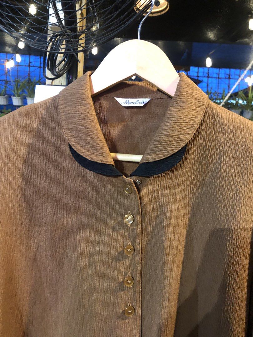 Moreiberis Brown Collared Button-Up Blouse (Category: Blouses) located in Cauayan City . Submitted by wholly.craaaft (Listing ID 1461018510, Image 3). Description: - Brown collared blouse from Moreiberis - Textured fabric - Button-up front - Black trim detail on collar - Long sleeves with button cuffs - Ideal for smart casual looks - Versatile: pairs well with skirts or trousers.