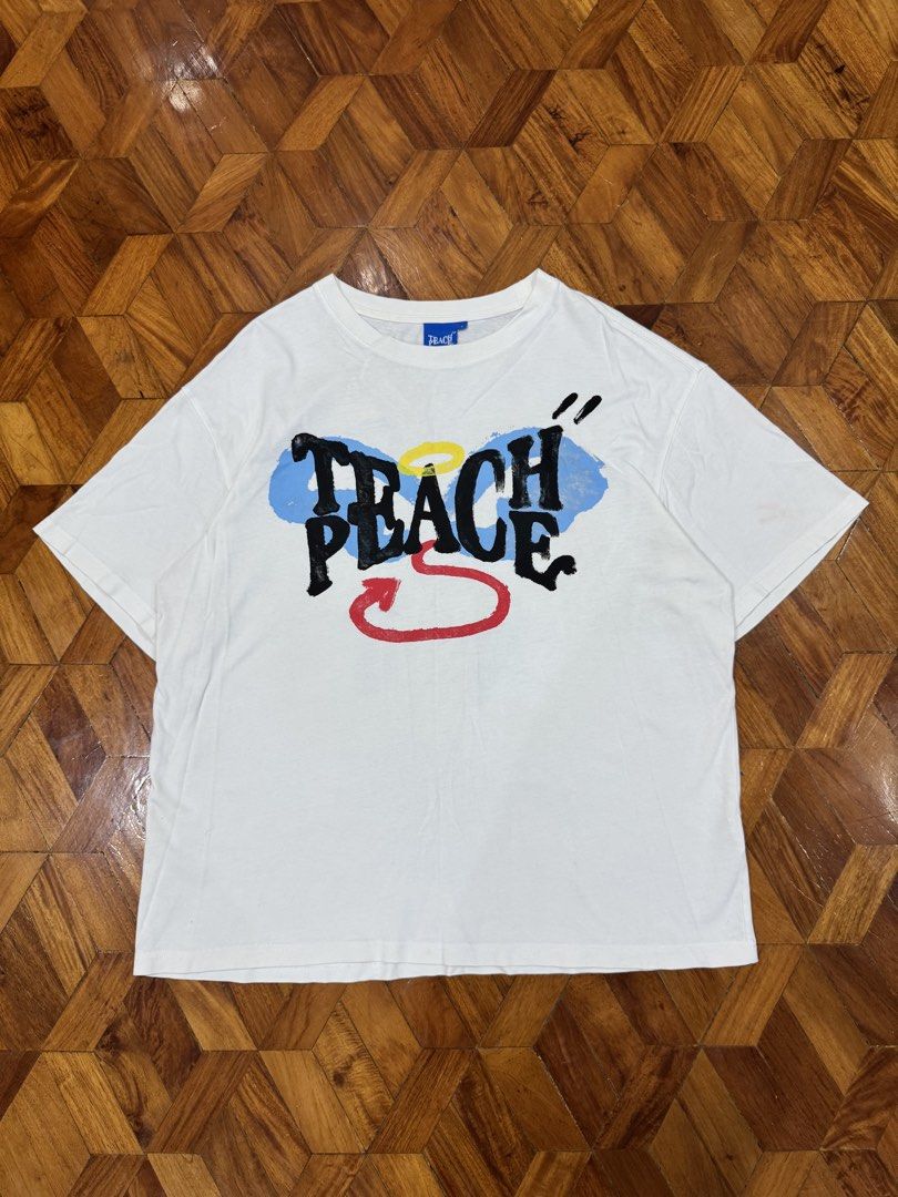 PEACH "Teach Peace" Graphic T-Shirt (Category: Tshirts & Polo Shirts ) located in Manila. Submitted by hypemeup.mla (Listing ID 1461089064, Image 1). Description: - White graphic t-shirt - "Teach Peace" design on the front - Devil and angel stick figure graphic on the back - Tag reads "PEACH" - Estimated size: Large (L) - Ideal for casual wear - 26x23 - excellent.