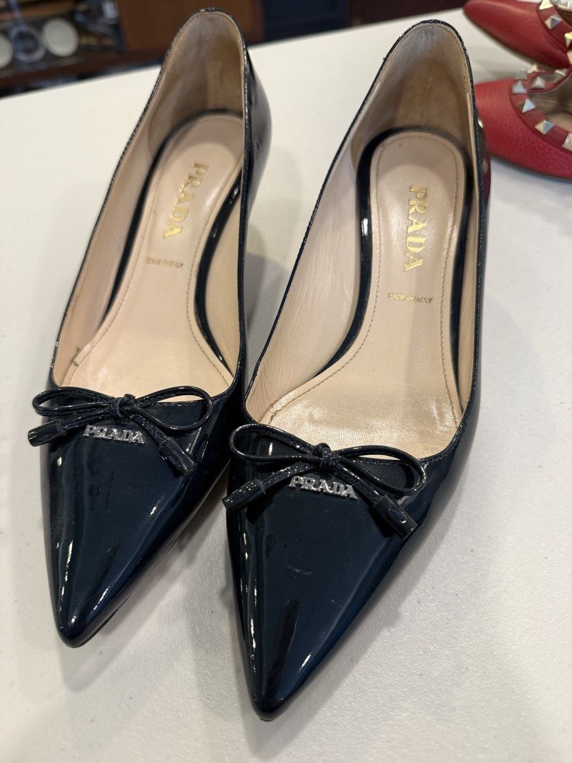 PRADA Black Patent Leather Bow Pumps — Size 37 (Category: Sneakers & Footwear) located in Pasig City. Submitted by marketplacesellinginc (Listing ID 1460995446, Image 1). Description: PRADA Black Patent Leather Bow Pumps — Size 37 Brand: Prada Size: 37 IT Made in: Italy Color: Black Material: Patent leather Style: Pointed-toe pumps with front bow and Prada logo detail Heel: Approximately 2 inches Condition: Pre-owned / Good condition * Beautiful 