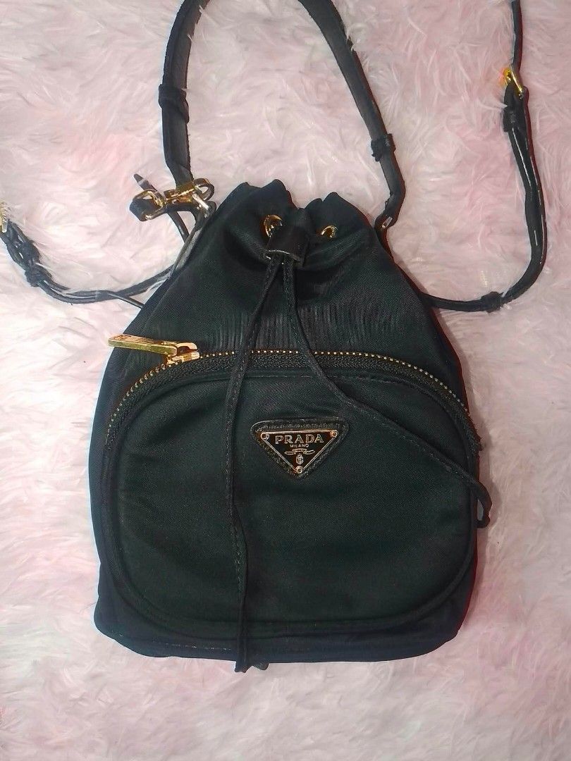 Prada Nylon Bucket Bag (Category: Luxury Bags & Wallets) located in Cainta. Submitted by mariss.luxx (Listing ID 1461025158, Image 2). Description: - Authentic Prada bucket bag - Black nylon material - Gold hardware details - Secure drawstring closure - Convenient front zip pocket - Interior with Prada logo lining and number tag - Adjustable shoulder strap for comfortable wear.