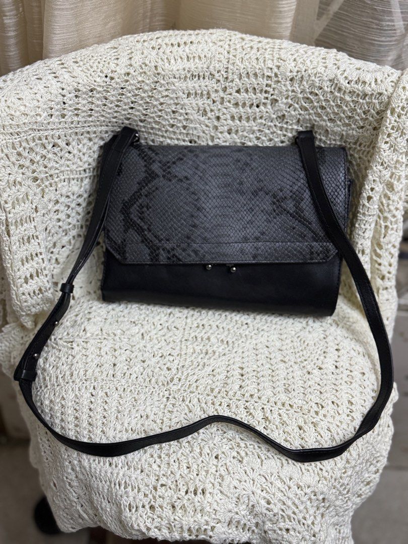 python-embossed foldover clutch / sling wallet (Category: Clutches) located in Bacolod City. Submitted by vintage_vogue6100 (Listing ID 1461040019, Image 2). Description: - python-embossed foldover clutch / sling wallet - Stylish black leather clutch - Eye-catching grey snake print flap - Secure magnetic closure with a small metal clasp - Multiple interior compartments and zippered pockets - Includes a detachable shoulder strap for versatility - 