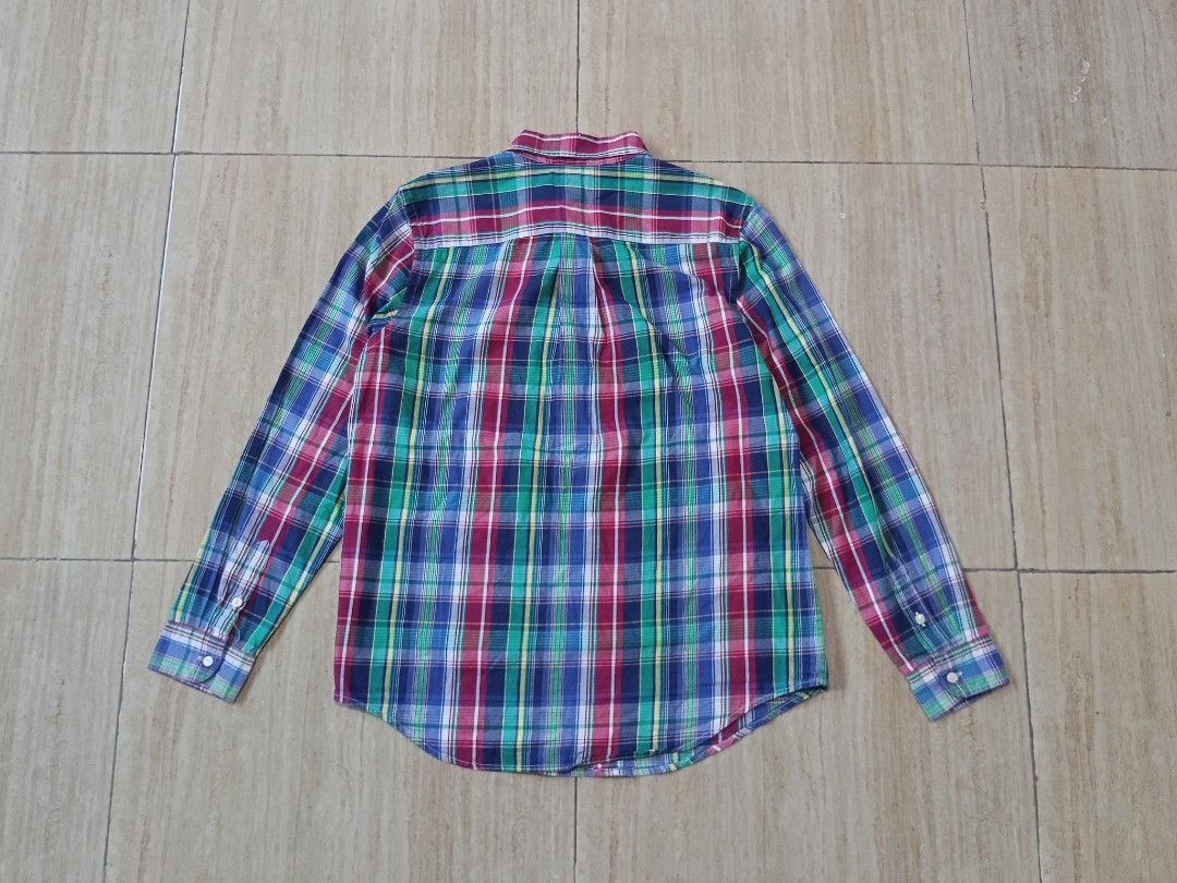 Ralph Lauren Plaid Button Down Shirt (Category: Tshirts & Polo Shirts ) located in Glan. Submitted by cpaharodde48008 (Listing ID 1460961847, Image 2). Description: - Classic Ralph Lauren plaid button-down shirt - Features a colorful pattern with blue, green, and red - Made of 100% soft cotton - Button closure and long sleeves - Perfect for casual wear or as a layering piece.