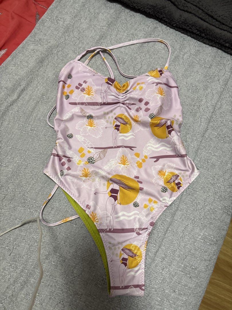 Reversible one-piece swimsuit (Category: Bikinis & Swimsuits) located in Mandaluyong City. Submitted by xxtin (Listing ID 1460924281, Image 1). Description: - Reversible - Adorable one-piece swimsuit - Fun floral and surfer girl print - Light purple with yellow and white flowers / Bright green on the other side - Straps tie at the back for adjustable fit - Flattering high-cut leg design - Ideal for beach days or pool parties Flaws: one of the str