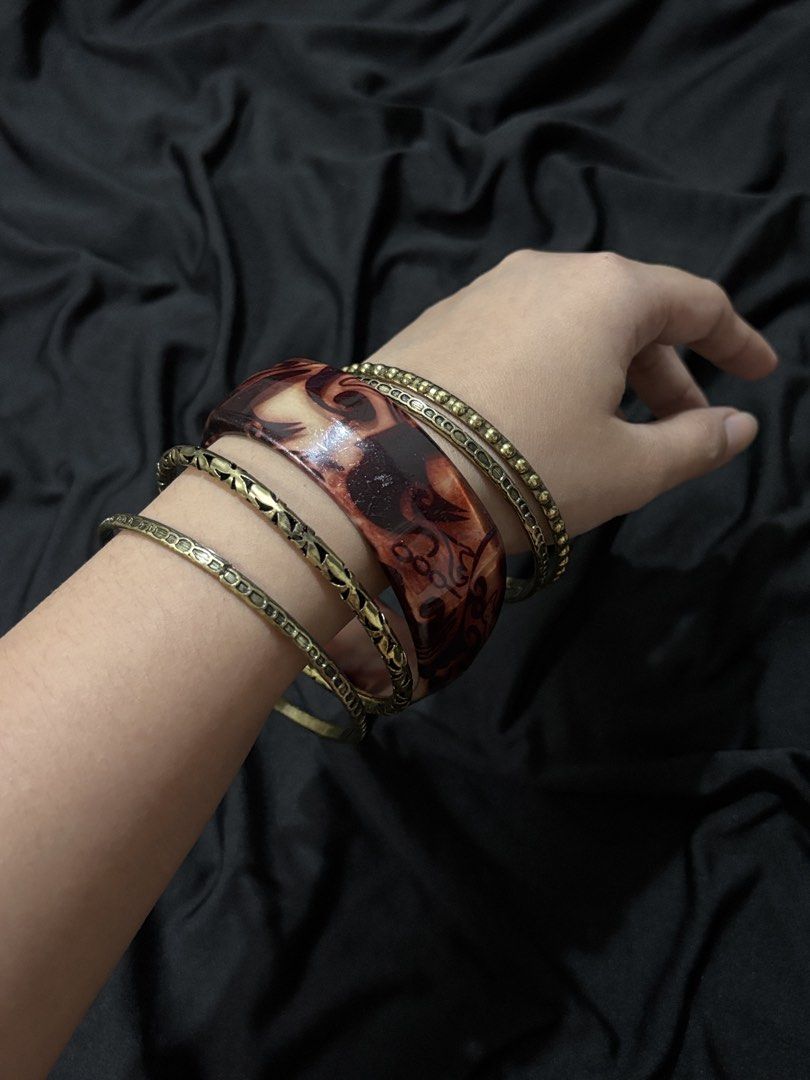 Set of 5 Mixed Bangles (Category: Bracelets) located in Manila. Submitted by rosewood.collectionz (Listing ID 1461066738, Image 2). Description: - Set of 5 bangles - Includes 1 wide tortoiseshell resin bangle with marbled pattern - Includes 4 thin gold-tone metal bangles - Two gold-tone bangles have a textured finish - Two gold-tone bangles have a hammered design - Perfect for mixing, matching, and stacking for various looks.