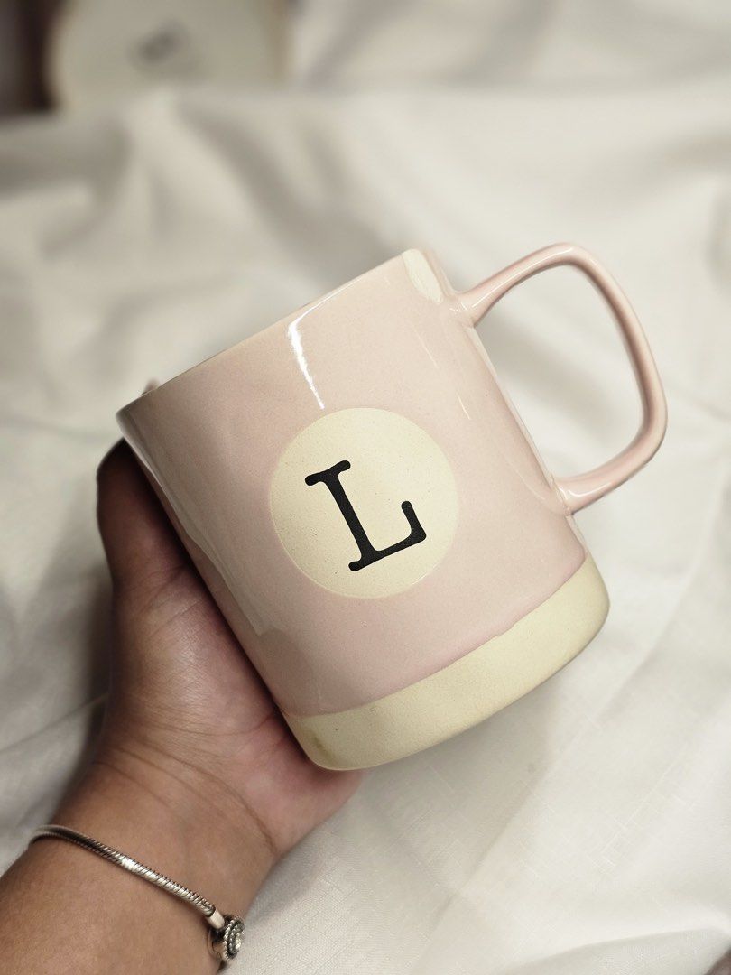 Set of 5 Unique Ceramic Mugs - Various Designs (Category: Coffee & Tea Tableware) located in Dasmarinas. Submitted by andreachalamet (Listing ID 1461055360, Image 3). Description: - Set of 5 charming ceramic mugs. - Pastel pink mug with 'L' initial. - Cream mug with a cheerful yellow handle. - Cream mug with a sophisticated dark green handle. - White mug adorned with a delicate pink and red floral design. - White mug featuring a unique pink ombre