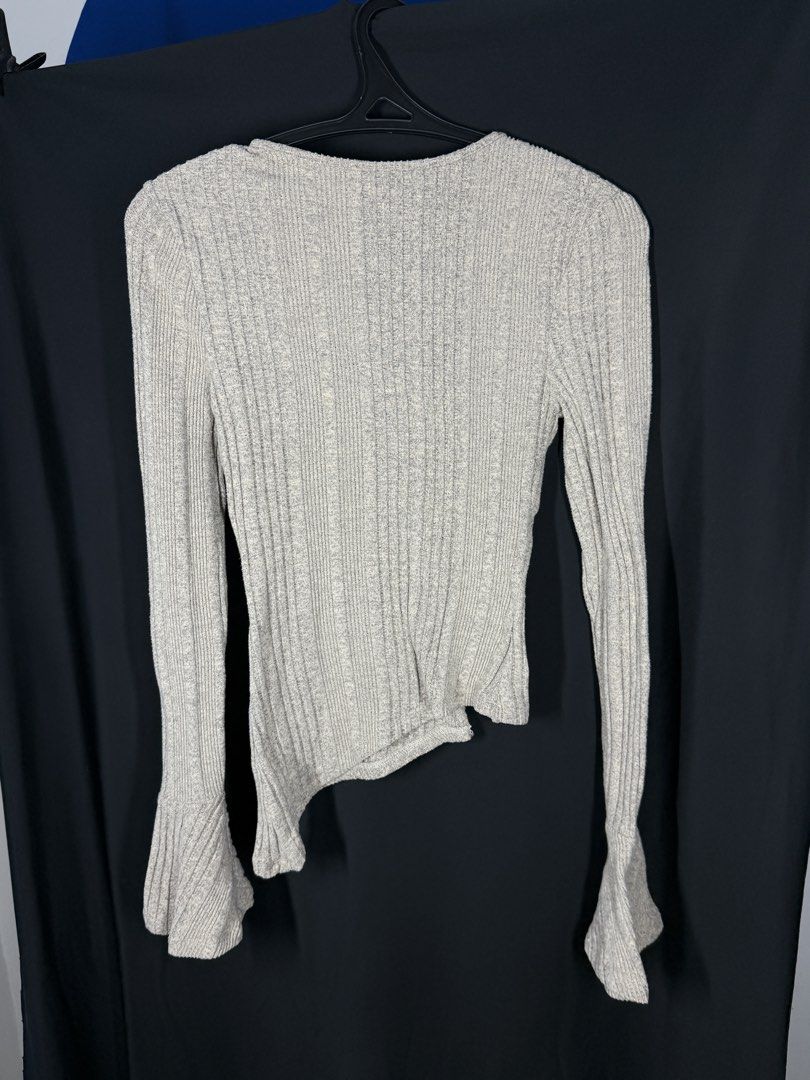 SHEIN Ribbed Bell Sleeve Asymmetrical Button Up Top (Category: Longsleeves) located in Angeles City. Submitted by lesmiz24601 (Listing ID 1460975091, Image 2). Description: - Light grey ribbed top from SHEIN - Long sleeves with unique bell cuffs - Asymmetrical hemline with button details down the front - Very unique and versatile design - Perfect for dressing up or down.