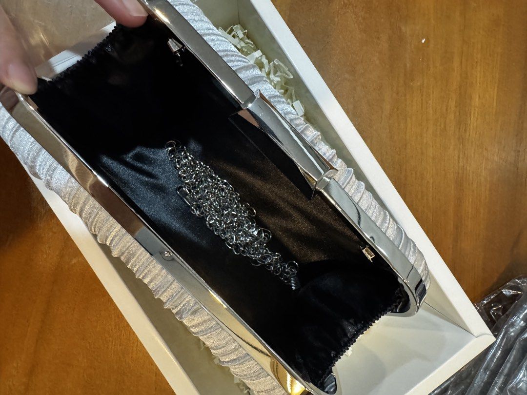 Silver Pleated Clutch Bag with Chain (Category: Clutches) located in Manila. Submitted by goodthingspreloved.92 (Listing ID 1461014594, Image 3). Description: - Stunning silver pleated clutch bag - Secure and sleek metal clasp closure - Luxurious black satin lining inside - Includes a detachable silver chain strap - Ideal for parties, weddings, and formal occasions.