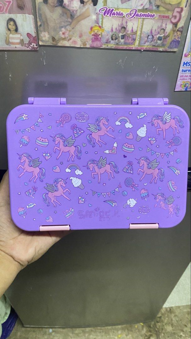 Smiggle Unicorn Lunch Box Purple (Category: Stationery & School Supplies) located in Manila. Submitted by mariamicaella24 (Listing ID 1461094164, Image 1). Description: - Adorable purple lunch box - Features a fun unicorn and ice cream design - Secure clasp closure for safety - Ideal for school lunches or snack packing - Easy to clean and maintain.