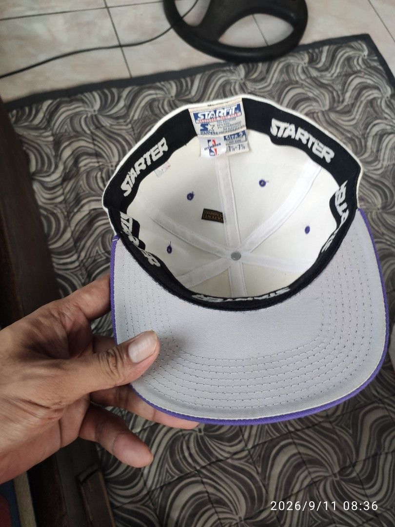 Starter Los Angeles Lakers NBA Snapback Cap (Category: Caps & Hats) located in Las Pinas. Submitted by vtg_sakalam2021 (Listing ID 1460956254, Image 2). Description: - Starter snapback cap for the Los Angeles Lakers. - Classic white with purple brim and details. - Features iconic Lakers logo on the front. - NBA and Starter logos also present on sides and inside. - Adjustable snapback closure for a custom fit. - Size: 7 1/8 - 7 3/8..
