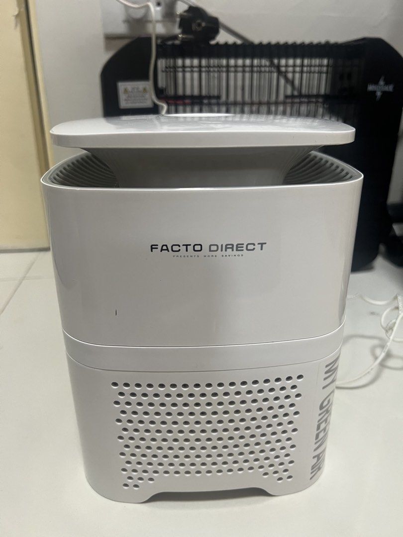 TABLETOP AIR PURIFIER (Category: Other Home Appliances) located in Cainta. Submitted by hunchester (Listing ID 1461081015, Image 3). Description: Type: Compact tabletop air purifier designed for small rooms or desktop use. Key Features: Features a top-mounted circular control button with an indicator light and louvered air outlet vents. Design: White molded plastic body with perforated intake grills near the base..
