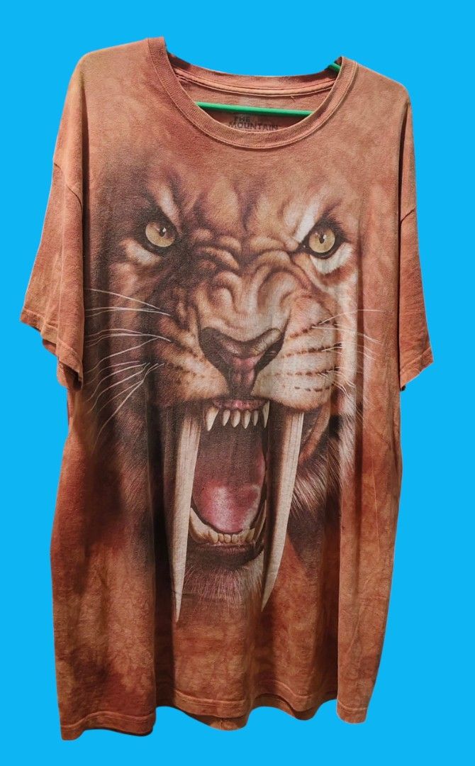The Mountain T-Shirt - Sabertooth Tiger Graphic (Category: Tshirts & Polo Shirts ) located in Camiling. Submitted by sundot_kalikot (Listing ID 1461002875, Image 1). Description: - Awesome graphic tee from The Mountain - Features a super detailed sabertooth tiger face print - Unique tie-dye style background - Short sleeves and crew neck - Great for animal lovers and statement outfits 22.5 x 32.5 issue: 1 pinhole, minimal sign of usage.