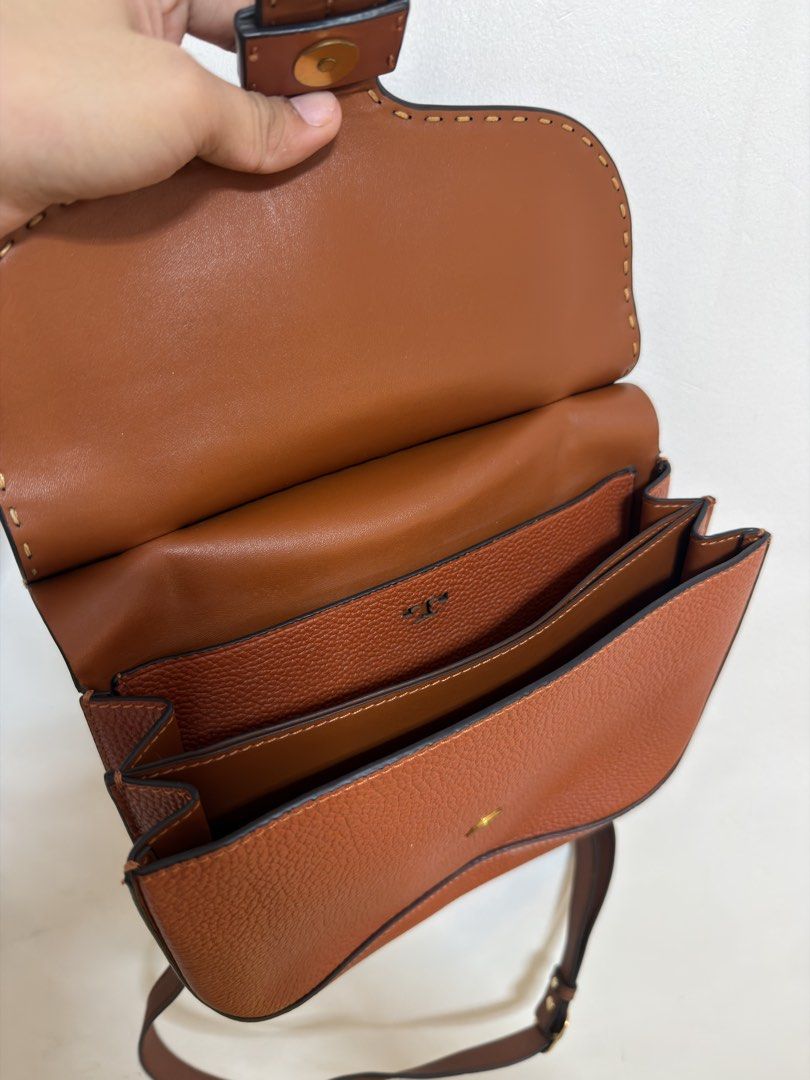 Tory Burch Brown Leather Shoulder Bag (Category: Luxury Bags & Wallets) located in Cavite. Submitted by misyelandco (Listing ID 1461107615, Image 2). Description: - Genuine brown pebbled leather shoulder bag - Signature Tory Burch logo clasp flap closure - Multiple interior compartments for organization - Adjustable shoulder strap for comfortable wear - Elegant stitching detail along the edges - Polished gold hardware accents.