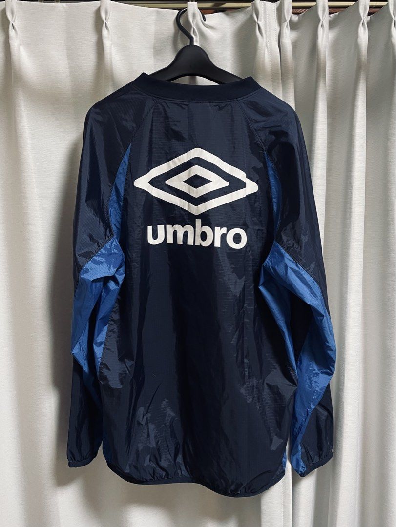 Umbro Navy Blue Windbreaker Jacket (Category: Coats, Jackets and Outerwear) located in Lapu Lapu. Submitted by mackoy221524 (Listing ID 1461085050, Image 1). Description: - Navy blue Umbro jacket - Blue accents on the sides - Prominent Umbro logo on the back - Smaller Umbro logo on the chest tag - Lightweight material, ideal for layering or light weather - Elasticated cuffs and hem - Great for sports or casual wear.
