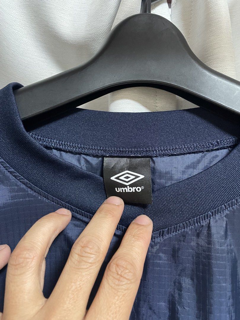Umbro Navy Blue Windbreaker Jacket (Category: Coats, Jackets and Outerwear) located in Lapu Lapu. Submitted by mackoy221524 (Listing ID 1461085050, Image 2). Description: - Navy blue Umbro jacket - Blue accents on the sides - Prominent Umbro logo on the back - Smaller Umbro logo on the chest tag - Lightweight material, ideal for layering or light weather - Elasticated cuffs and hem - Great for sports or casual wear.