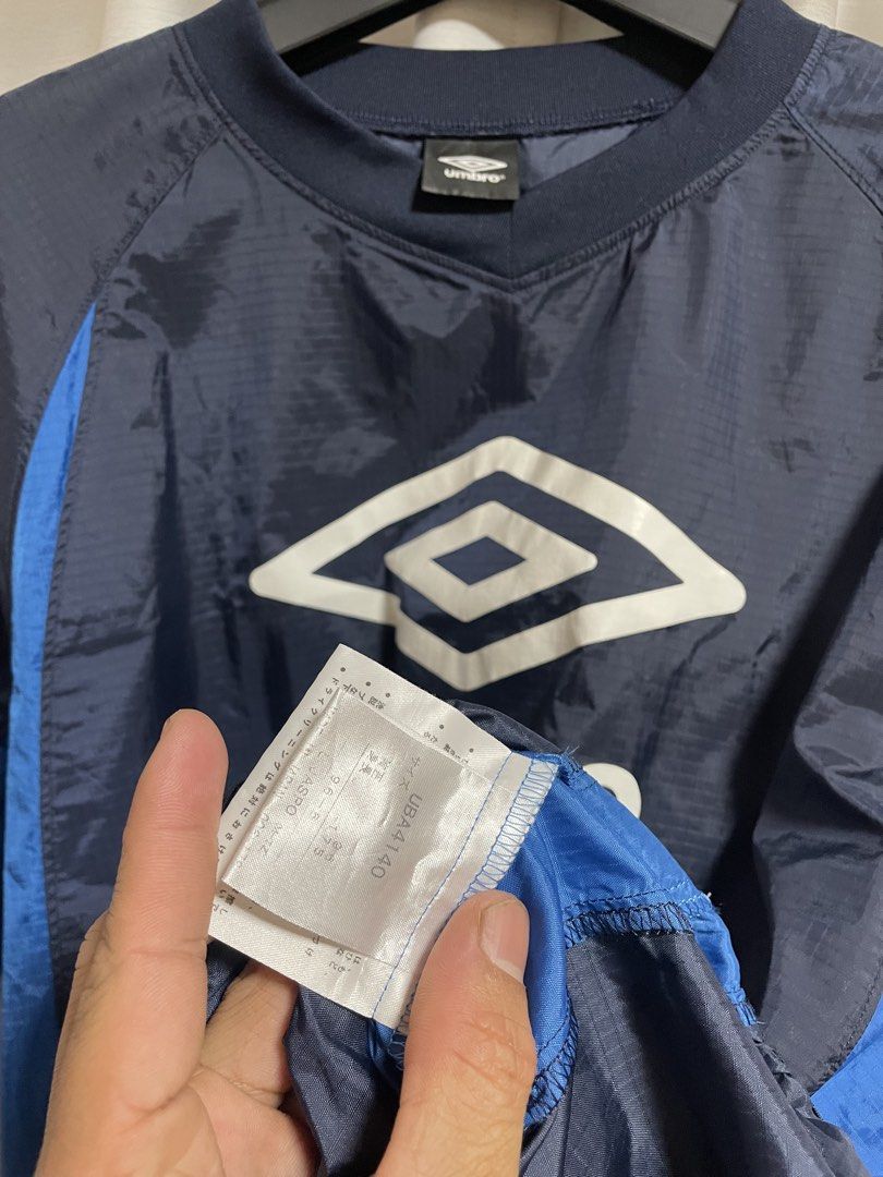 Umbro Navy Blue Windbreaker Jacket (Category: Coats, Jackets and Outerwear) located in Lapu Lapu. Submitted by mackoy221524 (Listing ID 1461085050, Image 3). Description: - Navy blue Umbro jacket - Blue accents on the sides - Prominent Umbro logo on the back - Smaller Umbro logo on the chest tag - Lightweight material, ideal for layering or light weather - Elasticated cuffs and hem - Great for sports or casual wear.