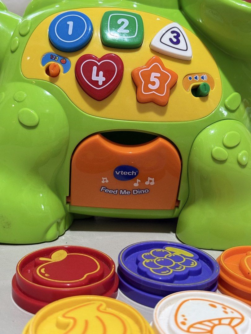 Educational toys VTech Chomp & Count Dino (interactive learning toys) (Category: Infant Playtime) located in Angeles City. Submitted by holyfabclothing (Listing ID 1460938661, Image 3). Description: VTech Chomp & Count Dino an interactive learning toy for toddlers featuring a green electronic dinosaur with colorful numbered buttons and a set of plastic food pieces. Toy Features Interactive Feeding: The dinosaur recognizes different colored food p
