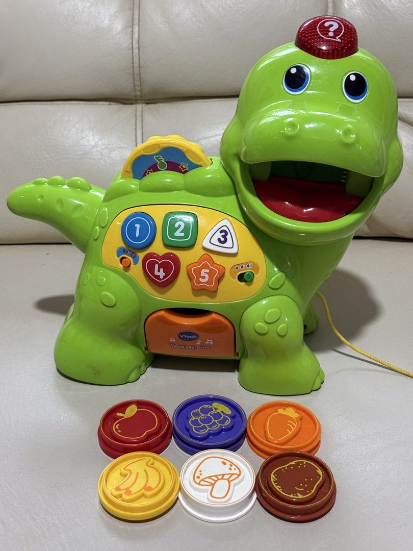Educational toys VTech Chomp & Count Dino (interactive learning toys) (Category: Infant Playtime) located in Angeles City. Submitted by holyfabclothing (Listing ID 1460938661, Image 1). Description: VTech Chomp & Count Dino an interactive learning toy for toddlers featuring a green electronic dinosaur with colorful numbered buttons and a set of plastic food pieces. Toy Features Interactive Feeding: The dinosaur recognizes different colored food p