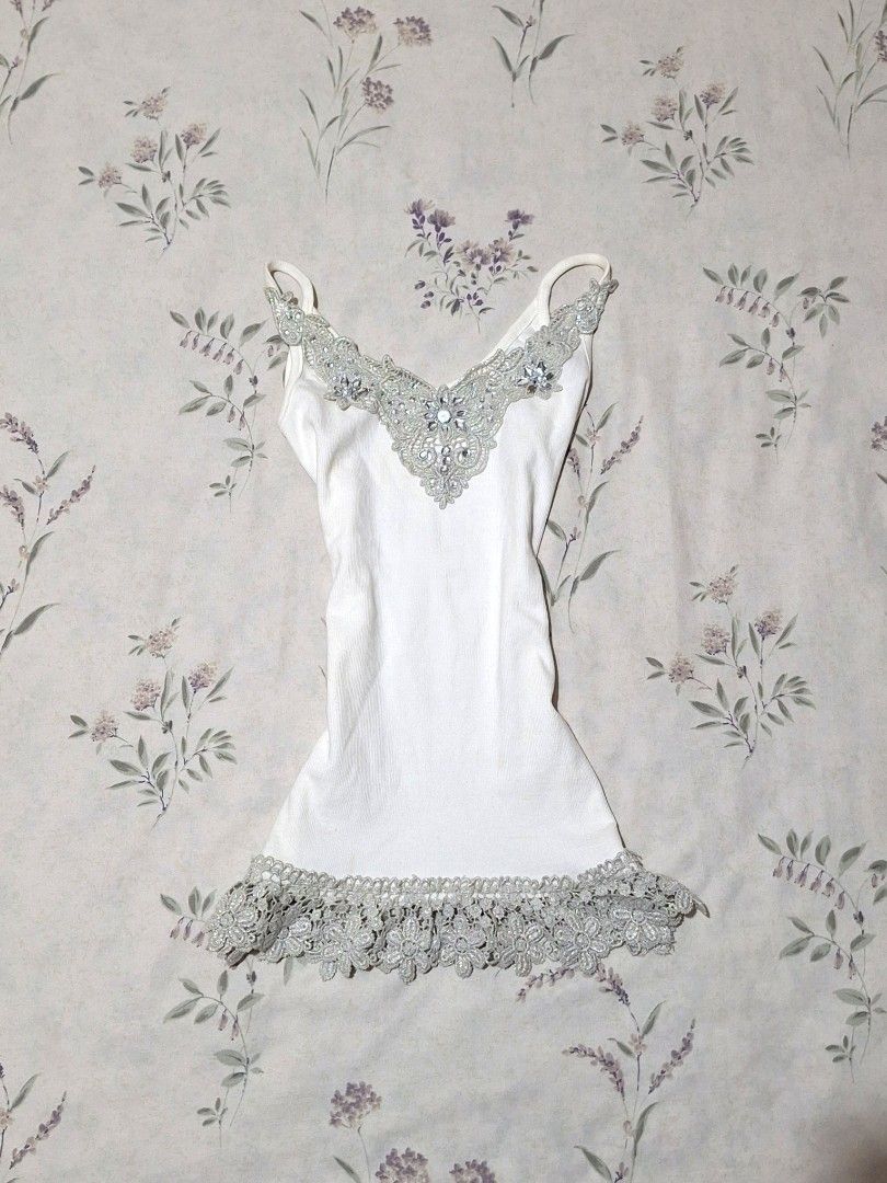 Whimsy fairy top white camisole (Category: Sleeveless) located in Taguig. Submitted by butterflypea.thrift (Listing ID 1460968320, Image 1). Description: - White ribbed camisole top - V-neckline with silver lace and rhinestone embellishments - Delicate silver lace trim on hem - Adjustable spaghetti straps - Versatile for layering or standalone wear.