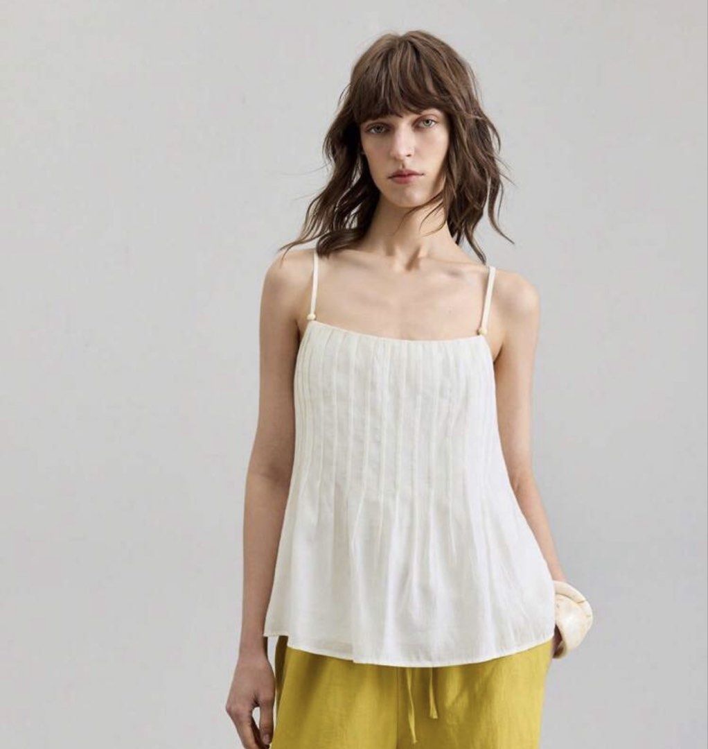 White Pleated Camisole Top with Adjustable Straps (Category: Sleeveless) located in Iloilo. Submitted by dabyladaby2 (Listing ID 1461051818, Image 1). Description: - Delicate white camisole top - Features elegant pleats down the front - Adjustable spaghetti straps with subtle bead accents - Relaxed, flowy silhouette - Versatile for layering or standalone wear - Ideal pairing for high-waisted skirts or pants- bust 32.9 in , length - 24.3 in.