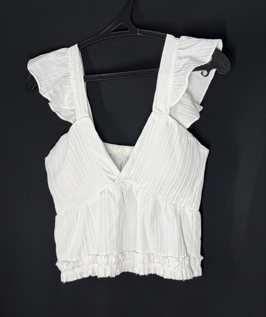White Ruffle Strap V-Neck Cropped Top (Category: Sleeveless) located in Angeles City. Submitted by lesmiz24601 (Listing ID 1460973274, Image 1). Description: - White cropped top - Ruffle straps - V-neckline - Textured fabric -S to medium - Elasticated hem - Pairs well with high-waisted bottoms - Ideal for summer days or nights out.
