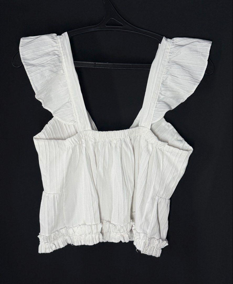 White Ruffle Strap V-Neck Cropped Top (Category: Sleeveless) located in Angeles City. Submitted by lesmiz24601 (Listing ID 1460973274, Image 2). Description: - White cropped top - Ruffle straps - V-neckline - Textured fabric -S to medium - Elasticated hem - Pairs well with high-waisted bottoms - Ideal for summer days or nights out.
