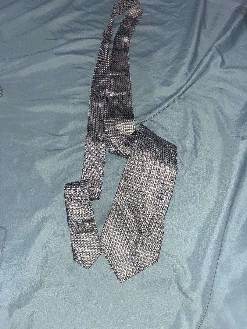 Yves Saint Laurent YSL Tie - Silver Houndstooth Pattern (Category: Ties) located in Tabuk. Submitted by collectors_thrift_shop (Listing ID 1461019972, Image 1). Description: - Silver tie with a sophisticated houndstooth pattern. - Crafted from 100% pure silk. - Proudly manufactured in Italy. - Features the iconic YSL logo on a black label. - A stylish addition to elevate your formal attire..