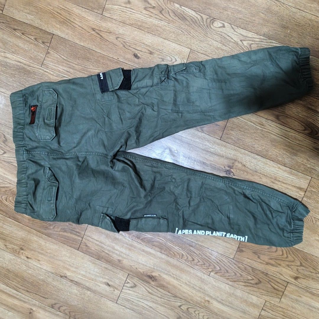 AAPE BY A BATHING APE Cargo Pants Olive Green (Category: Jeans) located in Manila. Submitted by narju1234 (Listing ID 1461124452, Image 3). Description: - Olive green cargo pants from AAPE by A Bathing Ape. - Size S. - Elastic waistband with adjustable belt. - Multiple pockets with secure velcro and button closures. - Signature AAPE branding on leg and back. - Unique 'APES AND PLANET EARTH' graphic detail on the leg..