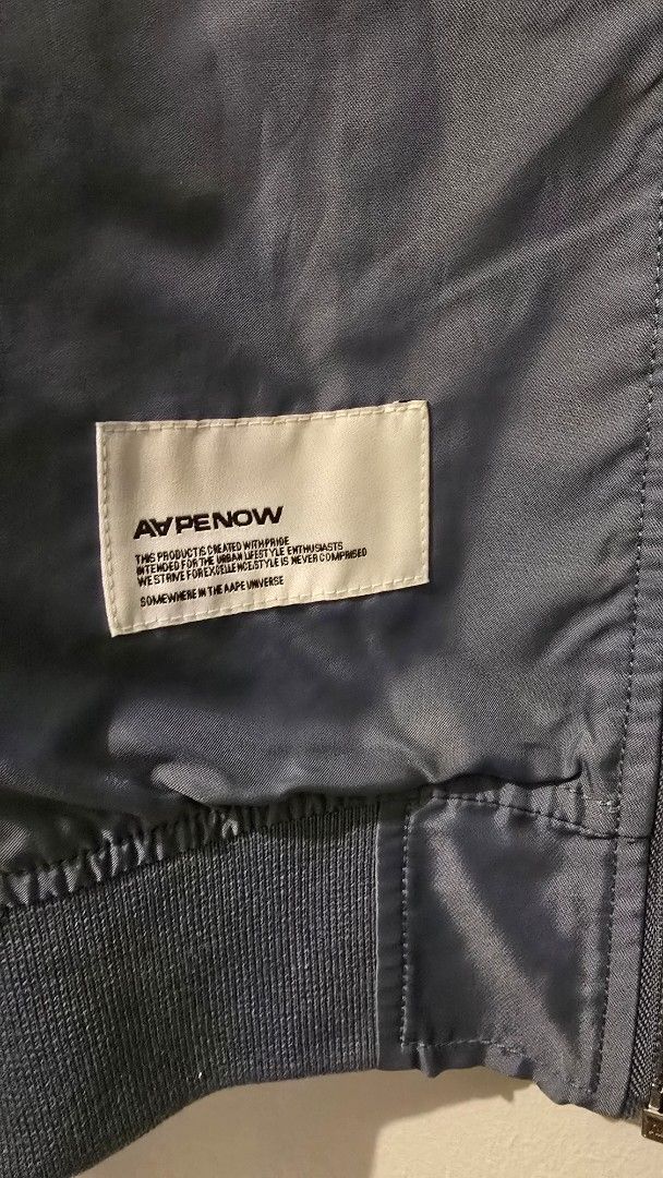 AAPE NOW Bomber Jacket (Category: Coats, Jackets and Outerwear) located in Quezon City. Submitted by ShoesManila (Listing ID 1461282153, Image 3). Description: AAPE Jacket Width 22 Length 27 Arm Length 27 Condition: Excellent Color rate: 10/10 - Grey AAPE NOW bomber jacket - Features AAPE NOW logo and text graphic on the front - Zipper closure - Convenient sleeve pocket - Ribbed collar, cuffs, and hem Ready to ship No COD Location: Diliman, QC.