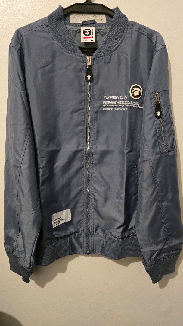 AAPE NOW Bomber Jacket (Category: Coats, Jackets and Outerwear) located in Quezon City. Submitted by ShoesManila (Listing ID 1461282153, Image 1). Description: AAPE Jacket Width 22 Length 27 Arm Length 27 Condition: Excellent Color rate: 10/10 - Grey AAPE NOW bomber jacket - Features AAPE NOW logo and text graphic on the front - Zipper closure - Convenient sleeve pocket - Ribbed collar, cuffs, and hem Ready to ship No COD Location: Diliman, QC.