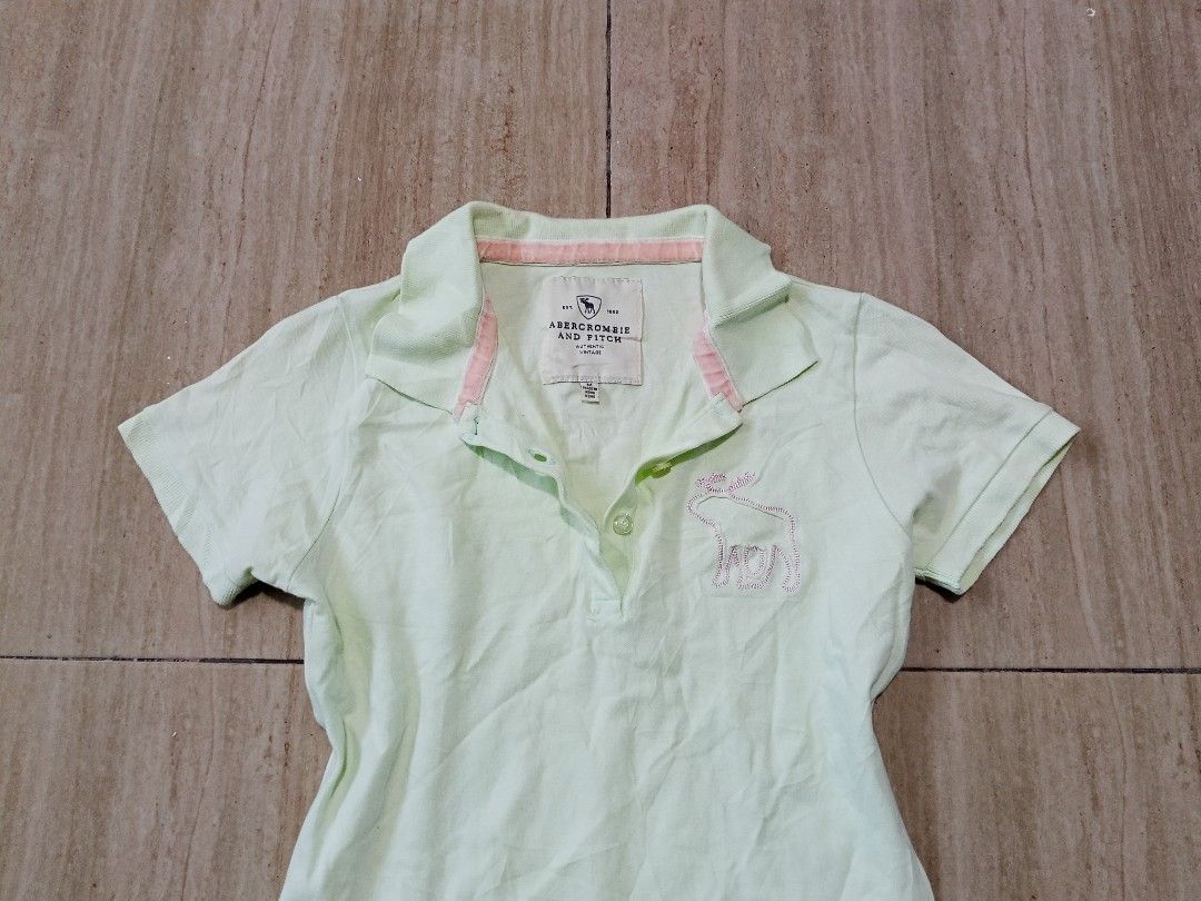 Abercrombie & Fitch womens top (Category: Activewear) located in Glan. Submitted by cpaharodde48008 (Listing ID 1461323624, Image 2). Description: - Cute light green Abercrombie & Fitch kids' polo shirt - Features a small embroidered bunny on the chest - Pink trim inside the collar for a pop of color - Short sleeves and button-up neckline - Ideal for everyday casual wear.