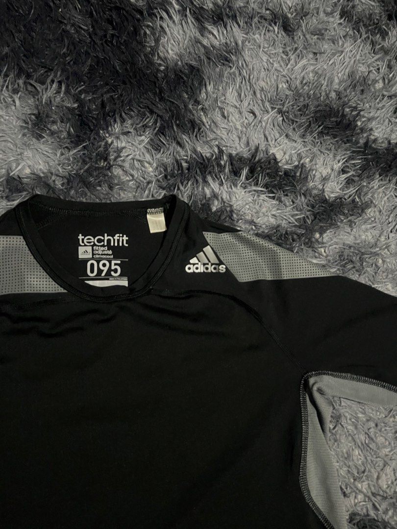 Adidas Techfit 095 Black Shirt (Category: Activewear) located in Cebu City. Submitted by drip_block (Listing ID 1461234565, Image 2). Description: Size M - Adidas Techfit shirt - Color: Black with grey shoulder/sleeve accents - Material: Polyester and elastane blend (check tag for specifics) - Fit: Comfortable, designed for performance - Ideal for: Workouts, sports, or casual wear.