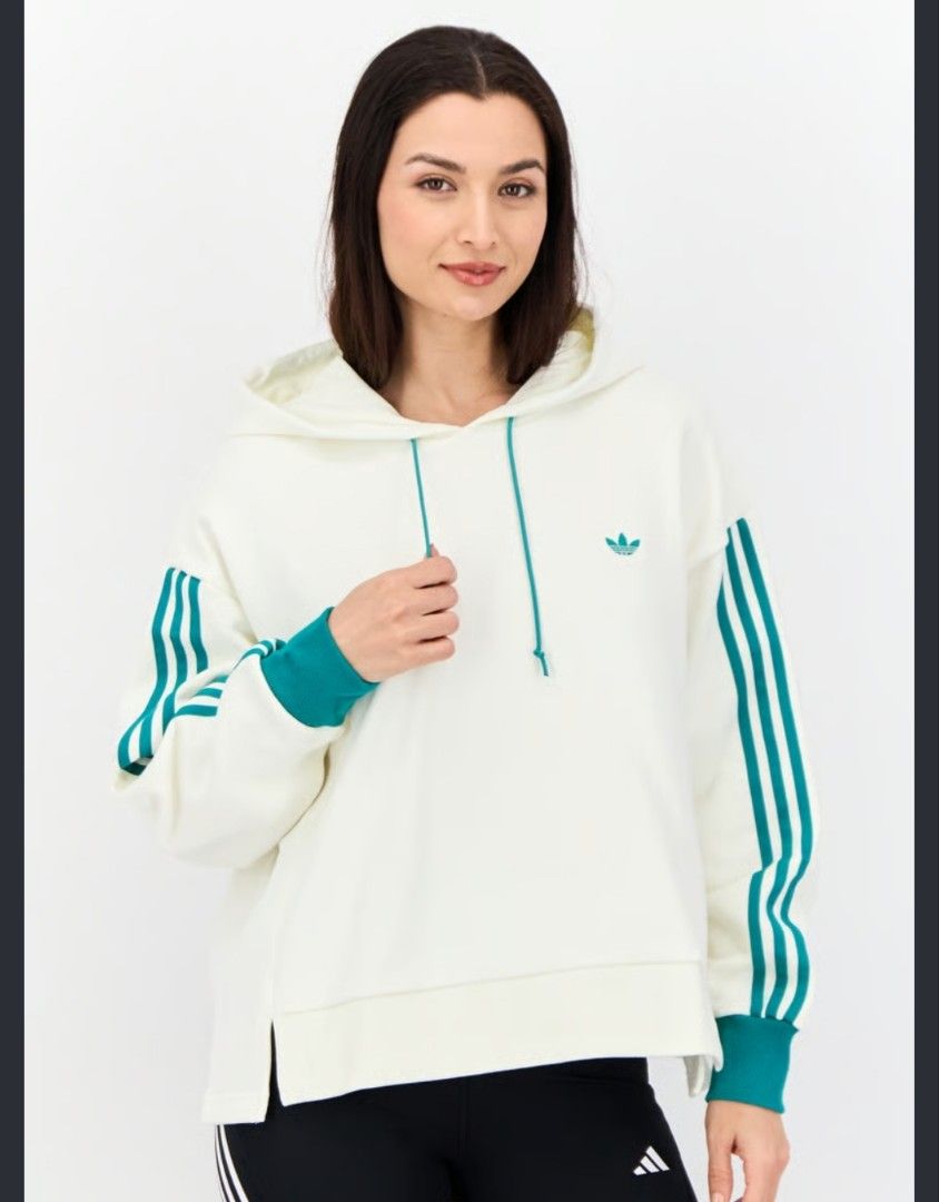 Adidas TRF Trefoil oversized pullover hoodie (Category: Coats, Jackets and Outerwear) located in Aroroy. Submitted by dr0p-a-dr1p (Listing ID 1461285646, Image 1). Description: - Classic white Adidas hoodie - Iconic green stripes on sleeves - Small green trefoil logo on front - Large trefoil graphic on back - Adjustable drawstring hood - Cuffed sleeves for a snug fit - Relaxed fit, perfect for everyday casual wear.