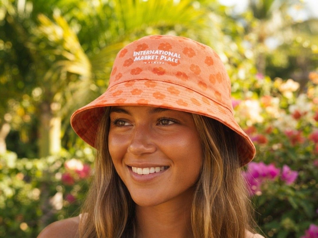 AOP Floral Bucket Hat (Category: Hats & Beanies) located in Binangonan. Submitted by yuristalin888 (Listing ID 1461308132, Image 1). Description: Bring a piece of Hawaiian paradise to your accessory collection with this vibrant orange bucket hat. The hat features a playful, all-over floral pattern in a slightly darker orange hue. Prominently embroidered on the front in white thread is the text "INTERNATIONAL MARKET PLACE" above "WAIKIKI". Crafted