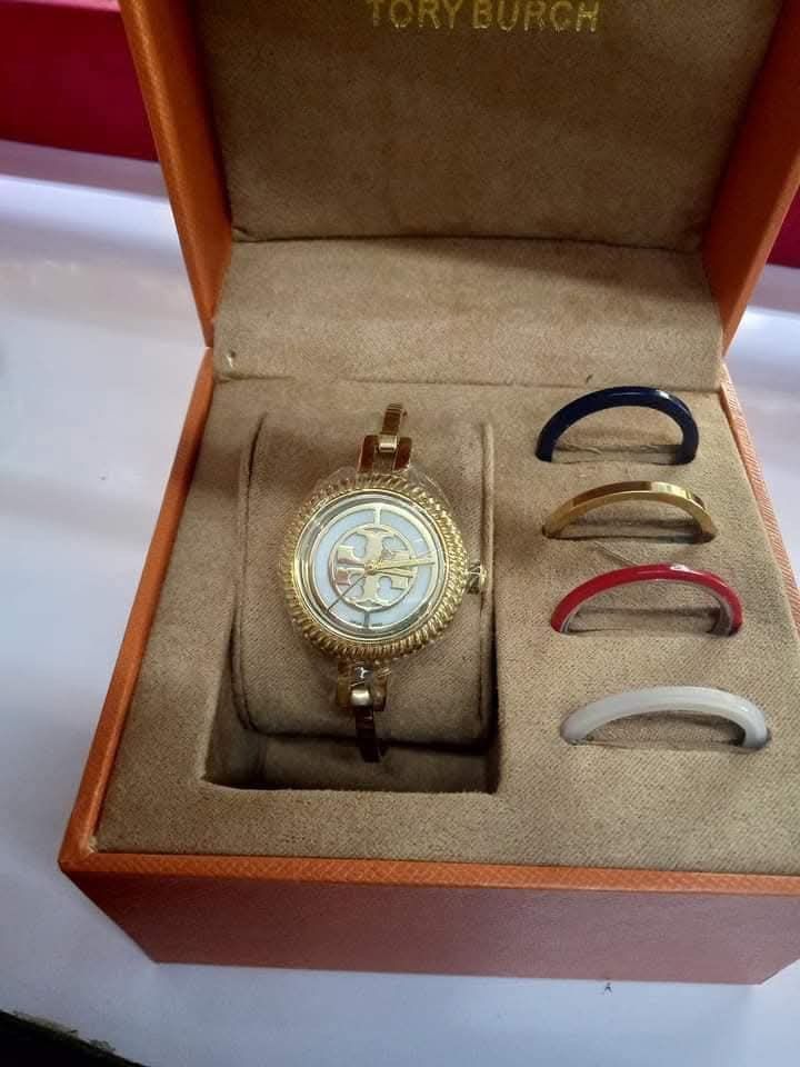 AUTH Tory Burch Watch with Interchangeable Bezels (Category: Women's Watches) located in Cavite. Submitted by marcelahongkay (Listing ID 1461250377, Image 1). Description: - Authentic Gold-tone Tory Burch Watch - Features a beautiful mother-of-pearl watch face with Tory Burch logo - Comes with interchangeable bezels in white, red, and blue - Includes original Tory Burch box - Makes a fantastic gift idea.