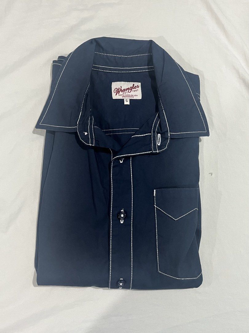 Authentic Wrangler Short Sleeve Button Up Shirt Size S (Category: Tshirts & Polo Shirts ) located in Quezon City. Submitted by angelo1412 (Listing ID 1461271262, Image 1). Description: - Brand: Wrangler - Color: Navy Blue - Original Price: ₱1,400 - Has no stain, rip, etc:) - Sleeve Length: Short Sleeve - Size: S - Details: White contrast stitching throughout, single chest pocket with pointed flap, button-up front - Style: Casual wear.