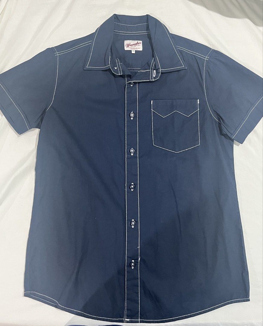 Authentic Wrangler Short Sleeve Button Up Shirt Size S (Category: Tshirts & Polo Shirts ) located in Quezon City. Submitted by angelo1412 (Listing ID 1461271262, Image 2). Description: - Brand: Wrangler - Color: Navy Blue - Original Price: ₱1,400 - Has no stain, rip, etc:) - Sleeve Length: Short Sleeve - Size: S - Details: White contrast stitching throughout, single chest pocket with pointed flap, button-up front - Style: Casual wear.